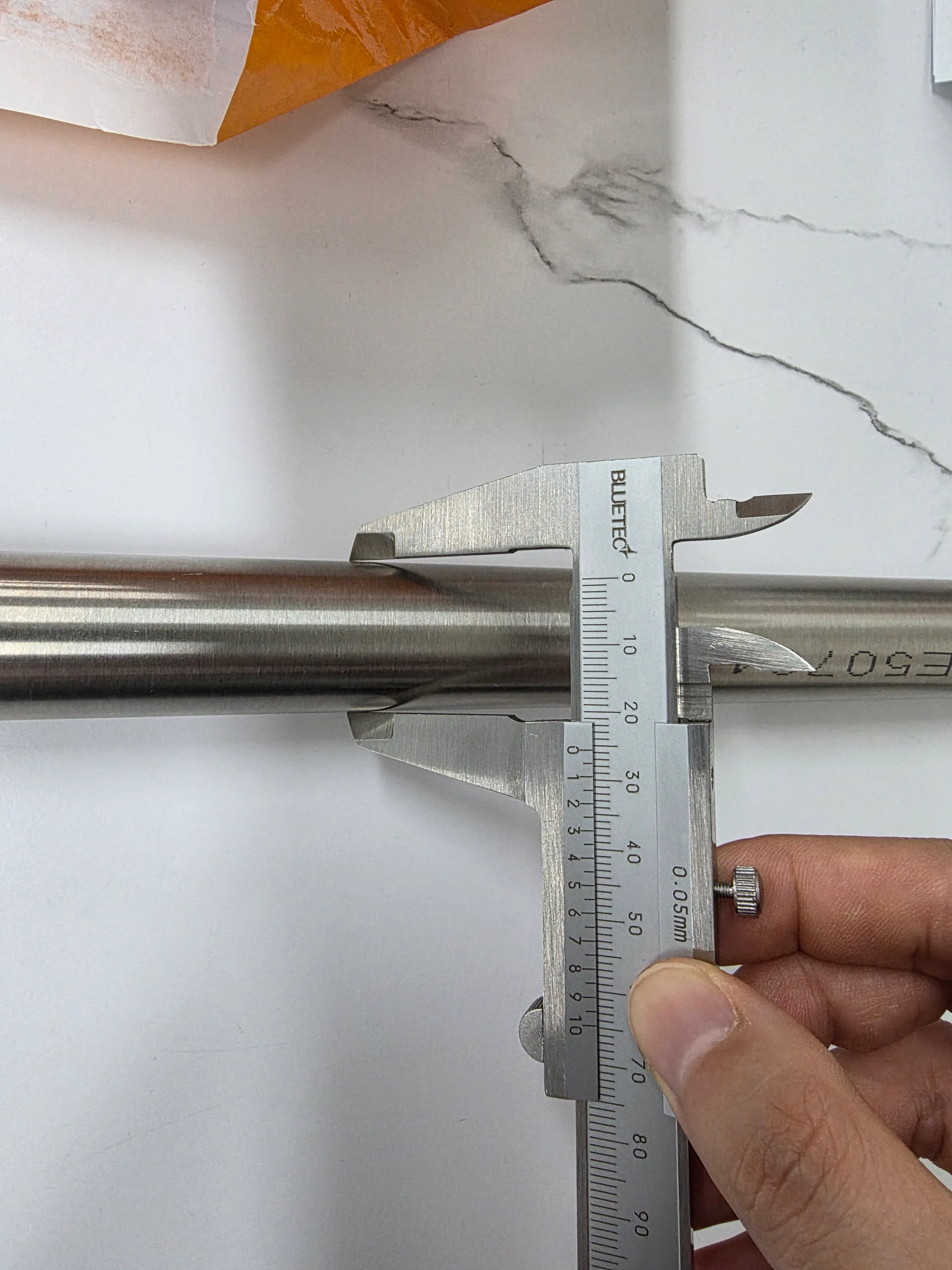 A vernier caliper measuring the outside dimension of fabricated piping