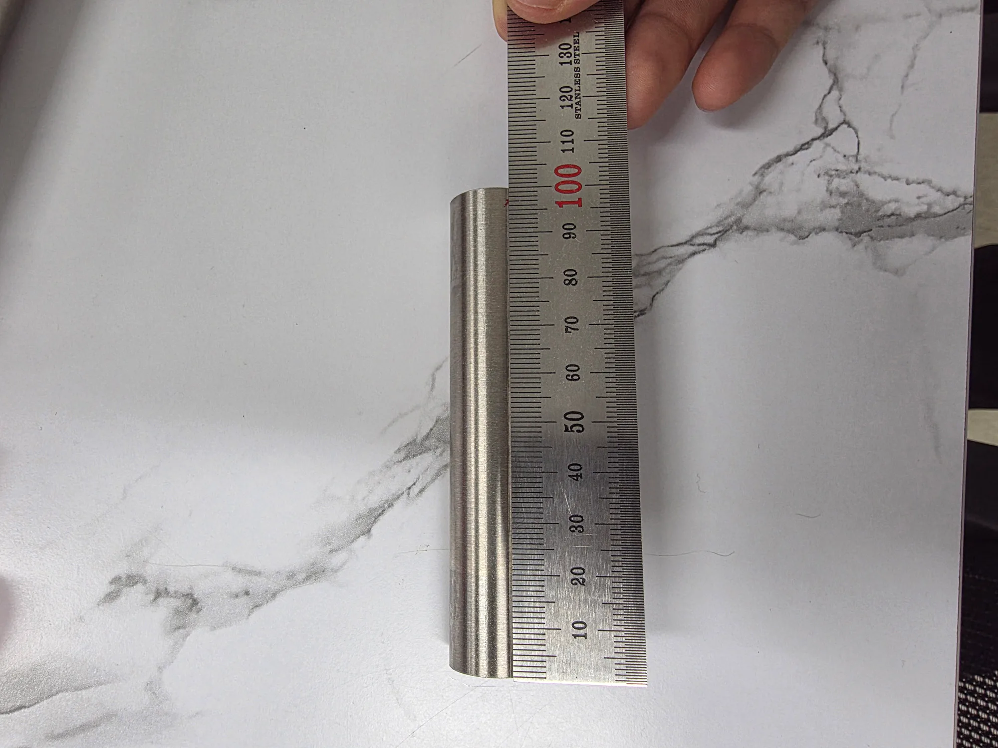 A steel rule placed against piping to check a dimension
